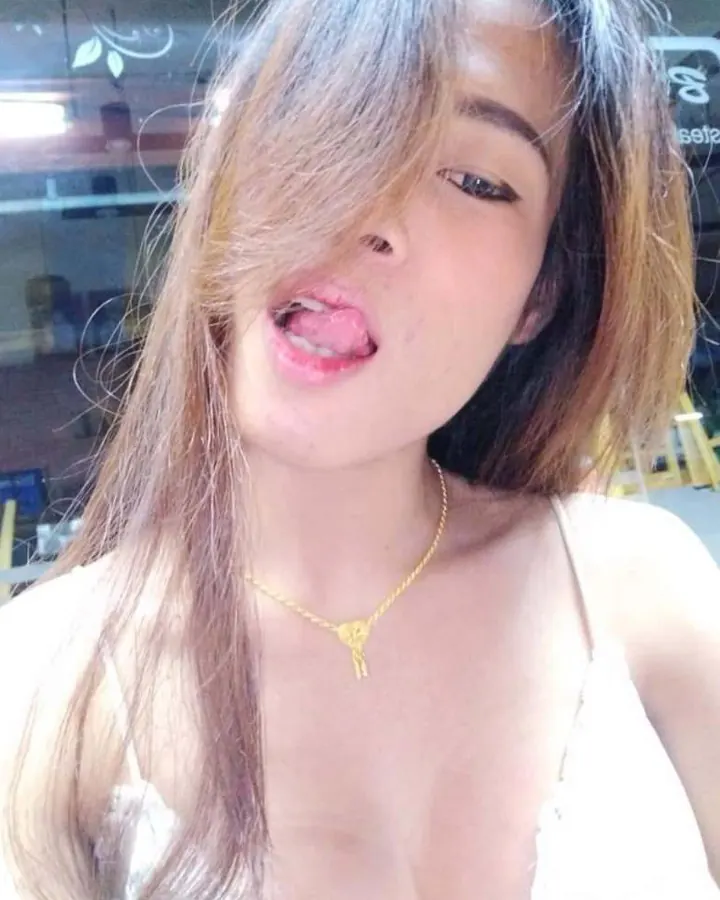 Femme trans asiatique aux cheveux longs noirs, prenant un selfie dans un miroir, en soutien-gorge léopard et culotte fleurie, avec un sweat gris baissé.
