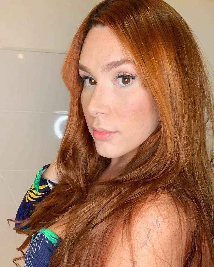 Emma, regard brun, cheveux roux longs, décolleté de tissu coloré, lumière douce