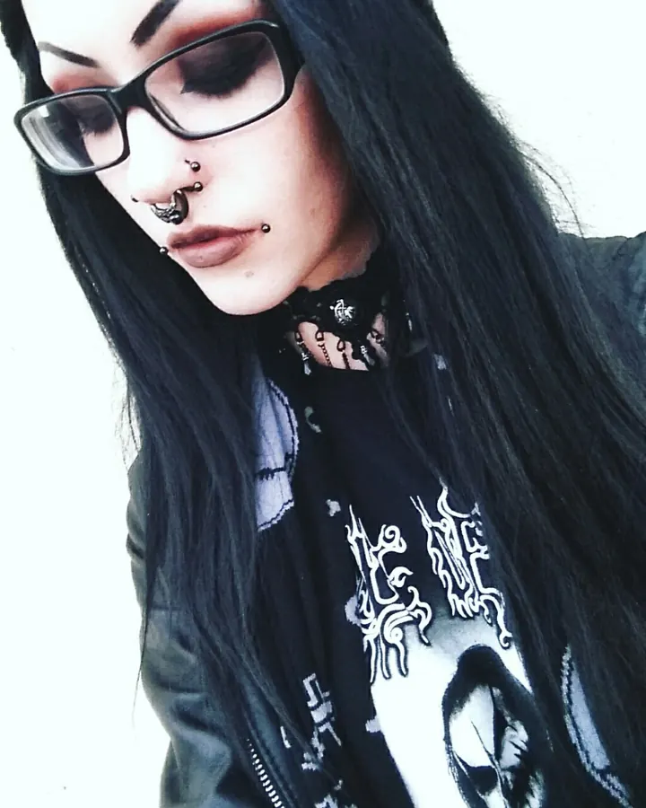 Femme trans asiatique aux cheveux bruns-noirs, en haut blanc, posant devant un fond rose