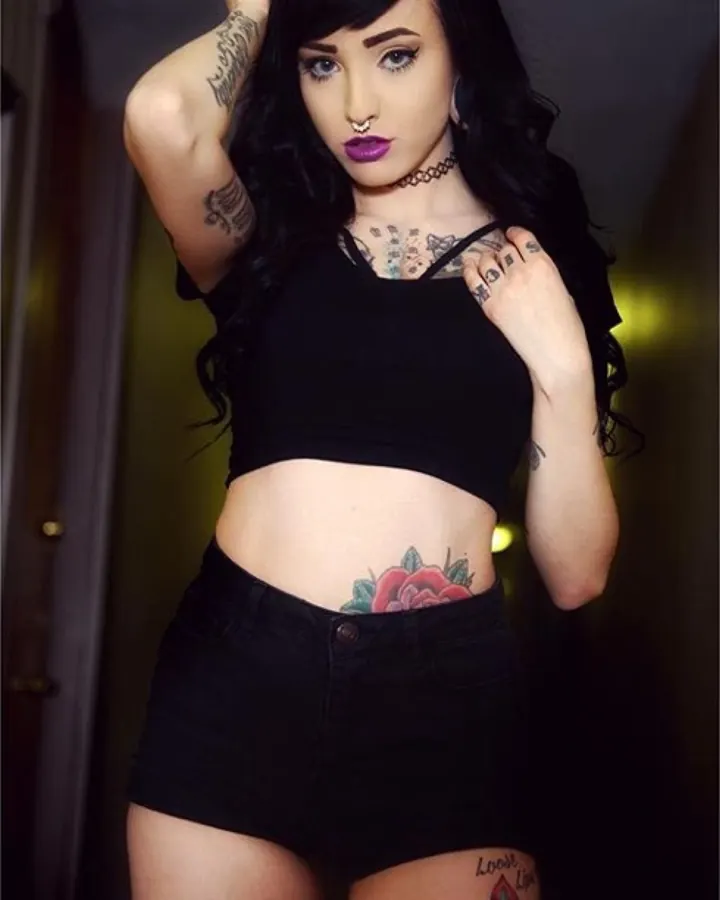 Femme trans en lingerie noire, posant sur un lit, regardant vers le haut